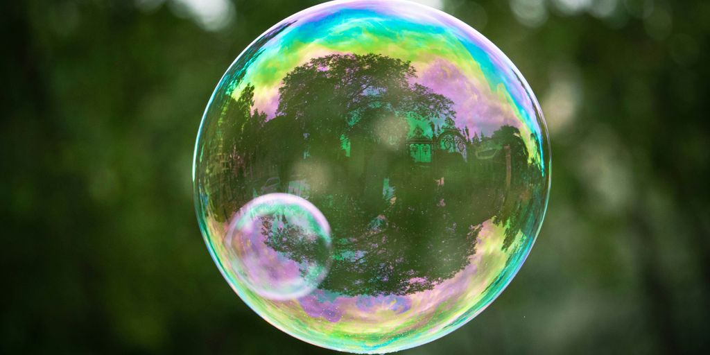 a soap bubble floating in the air with trees in the background