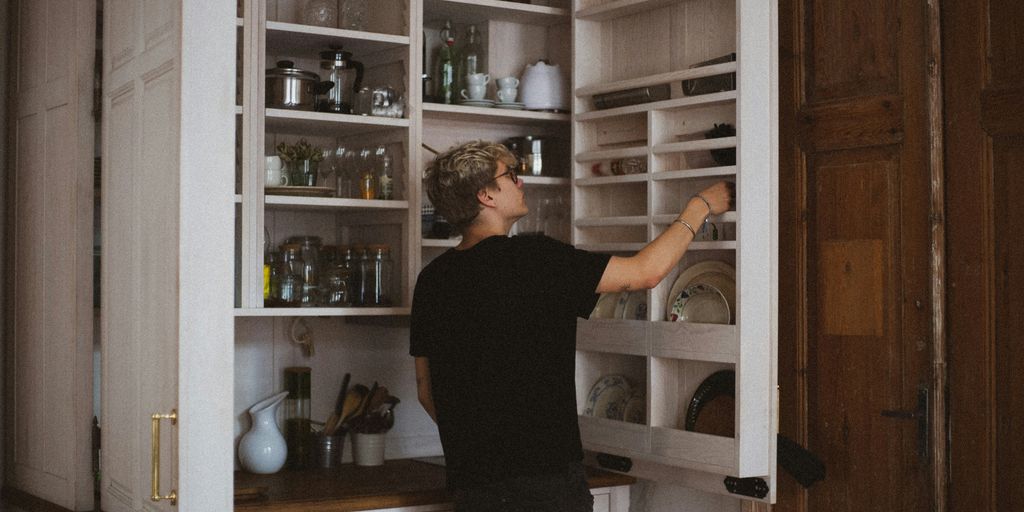 man standing near cabinet reaching plate