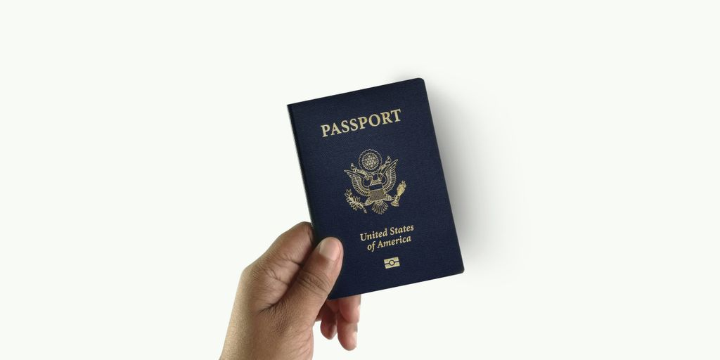 a hand holding a passport over a white background