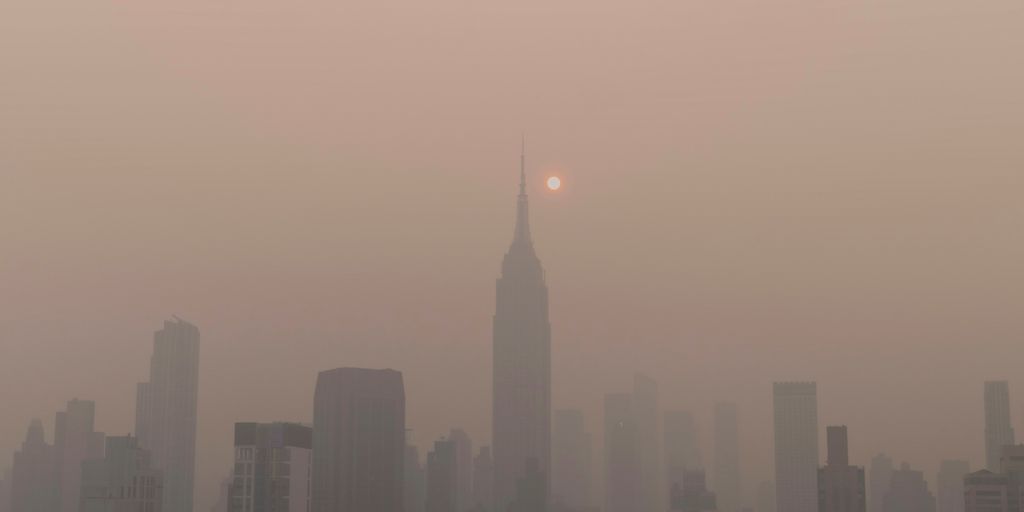 a foggy city skyline with the sun in the distance