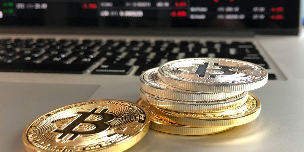 Bitcoin coins on a digital graph chart with upward trend, financial trading screens in the background