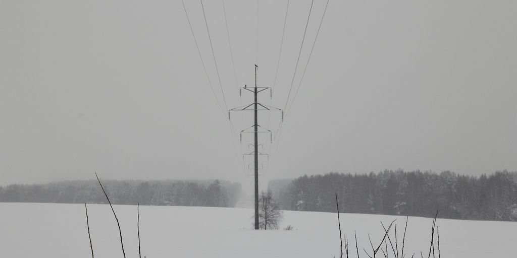 a snow covered field with power lines in the distance