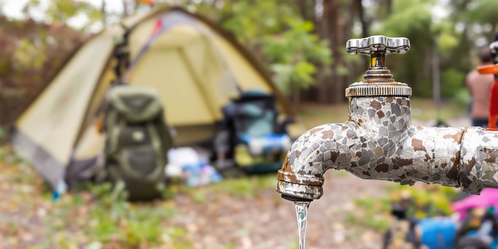 Leaky faucet outdoors with camping gear.