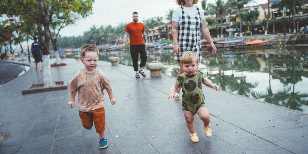 a group of people walking down a sidewalk next to a lake