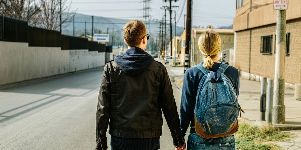 man holding hands of woman walks on concrete road