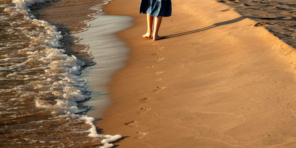 A person walks along the beach shoreline.