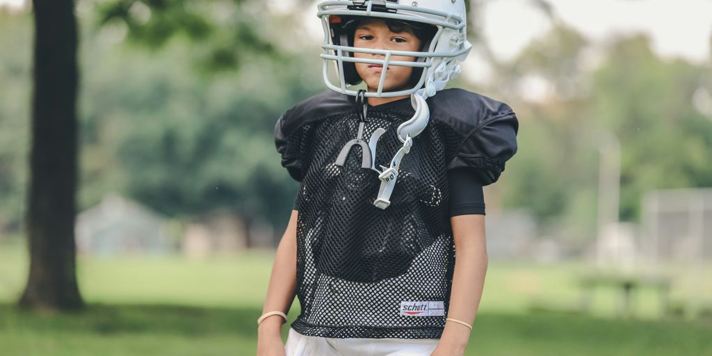 selective focus photography of boy wearing American football gear