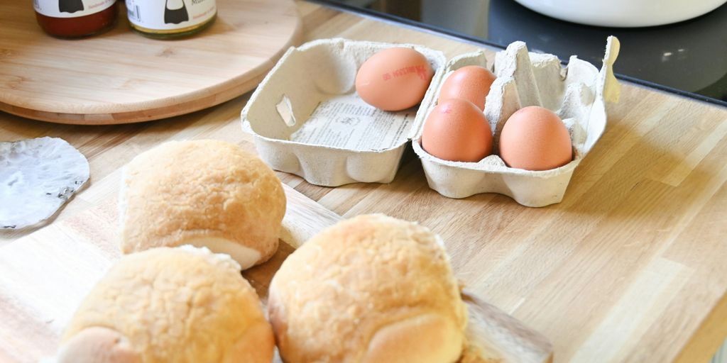a wooden cutting board topped with buns and eggs