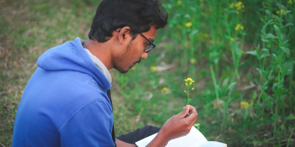 a man sitting in a field reading a book