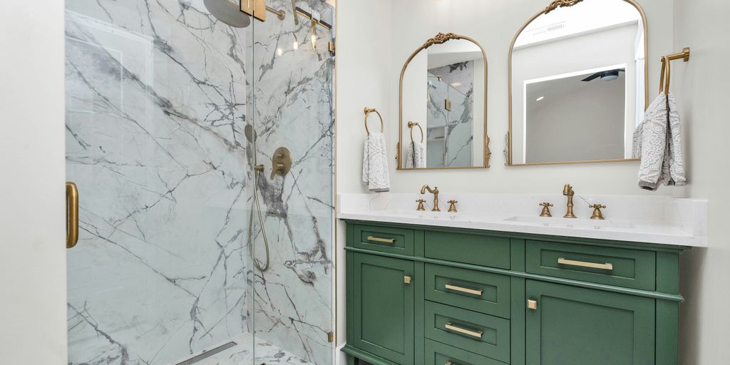 a bathroom with green cabinets and a marble shower