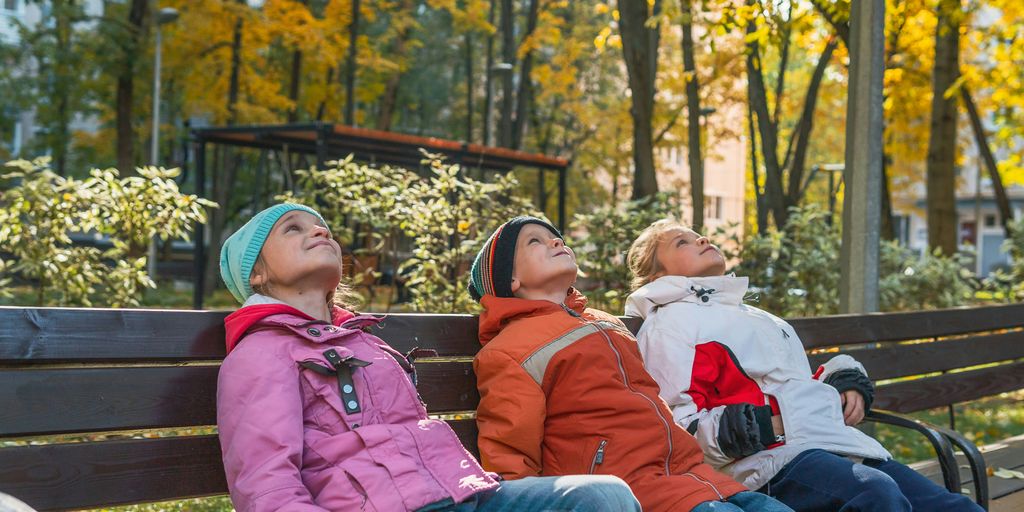 three people sitting on a bench in a park