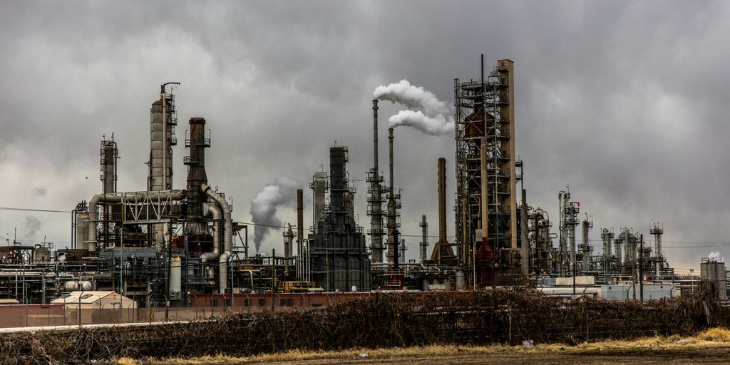 factories with smoke under cloudy sky