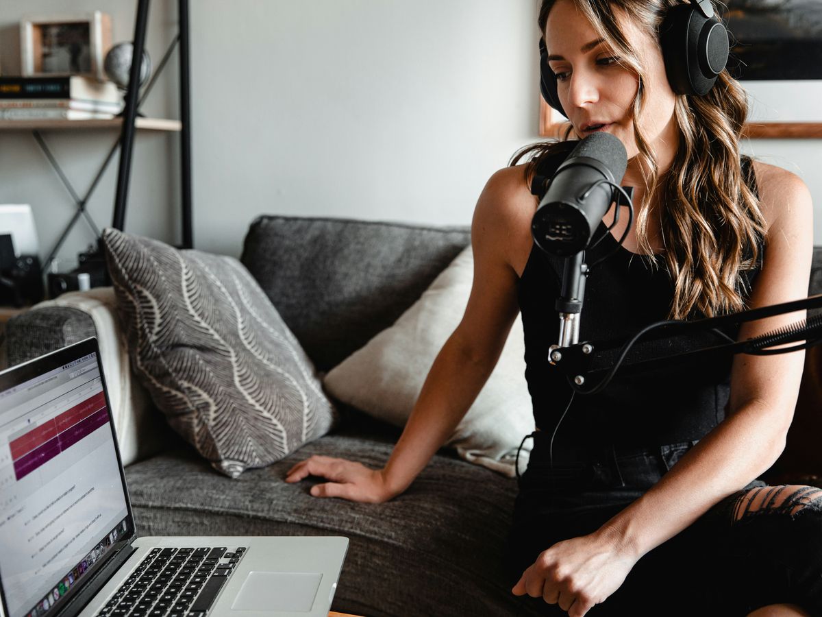 woman in black tank top sitting on couch using macbook