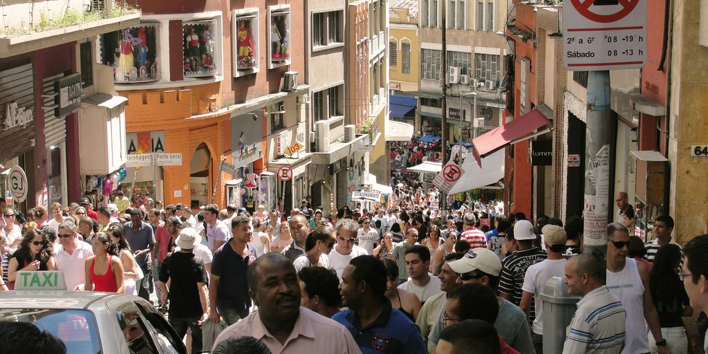 a crowd of people walking down a street next to tall buildings