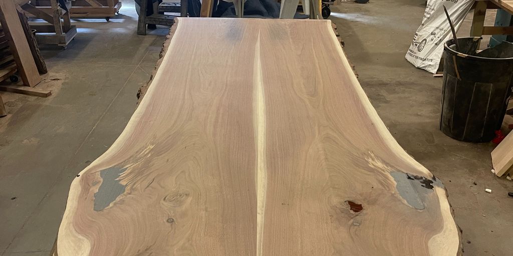 Large wooden slab with natural edges in carpentry workshop.