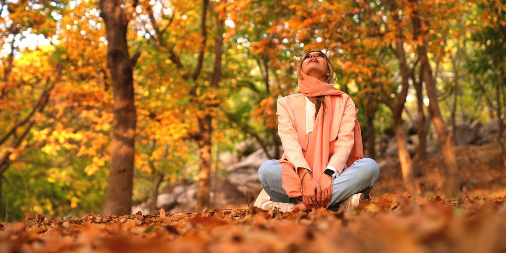 a woman sitting on the ground in a forest