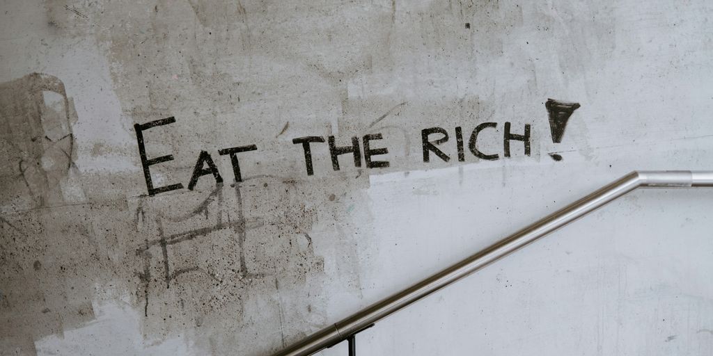 graffiti on a wall that says eat the rich
