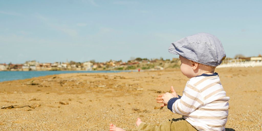 sitting toddler on seashore at daytime