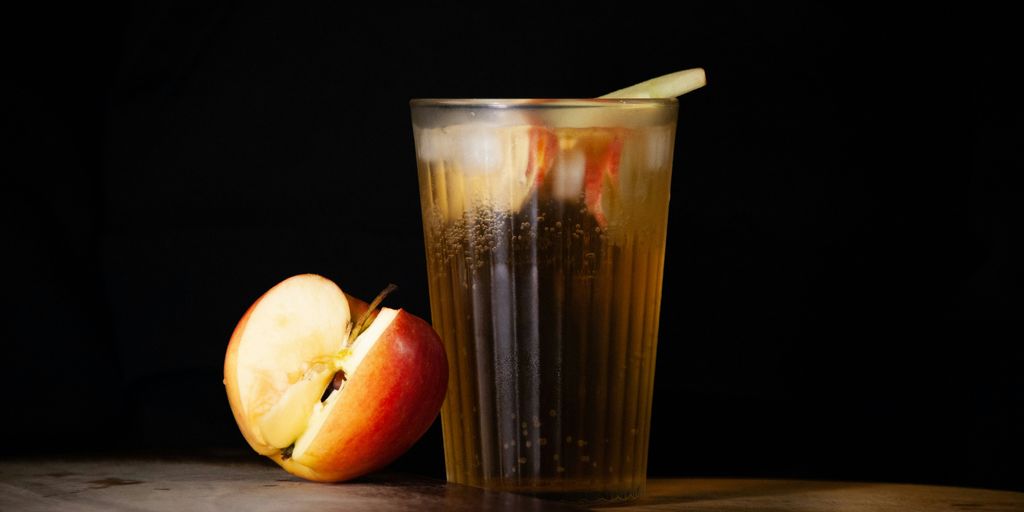 An apple and a glass of liquid on a table