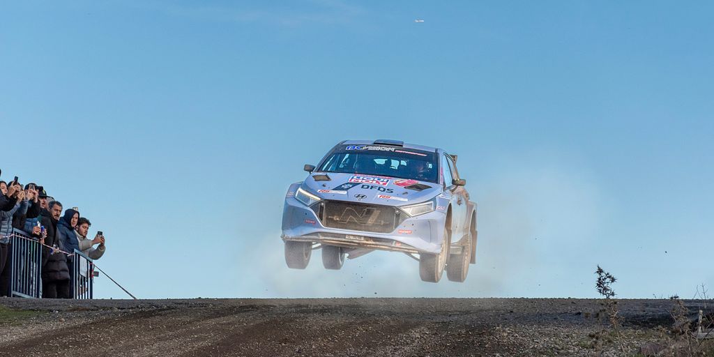 a silver car jumping over a dirt road