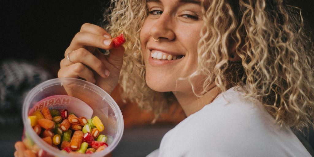 woman in white long sleeve shirt holding clear plastic container with candies