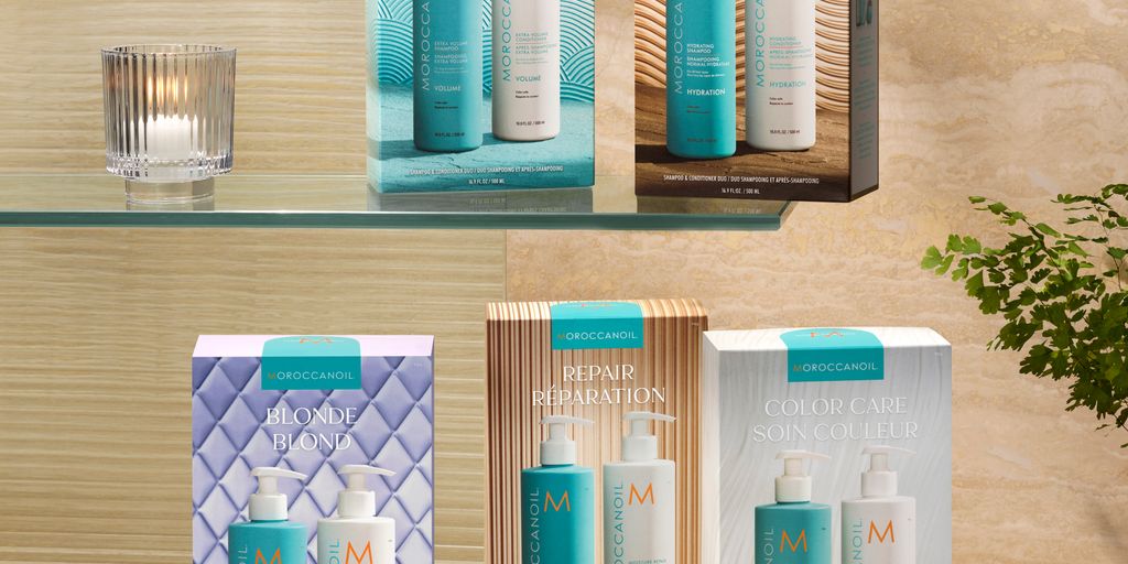 Haircare products displayed against a marble background with plants.