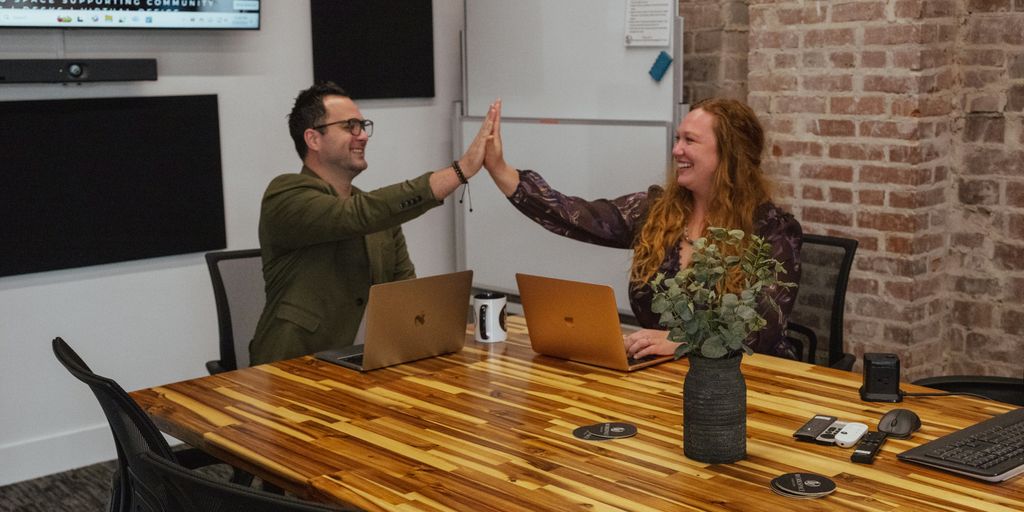 Two people high-fiving in a meeting room.