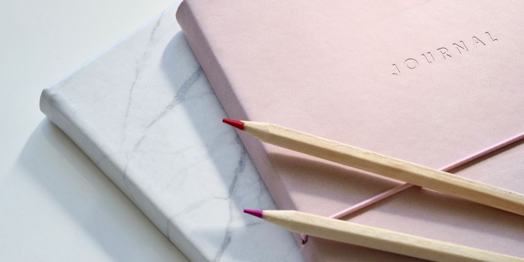 red and purple coloring pencils on pink journal