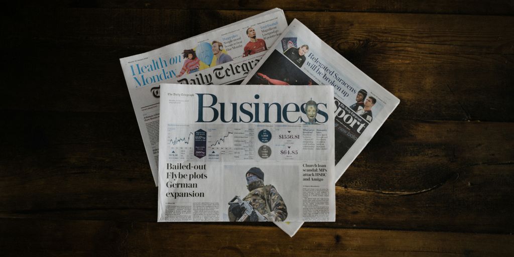 a stack of newspapers sitting on top of a wooden table