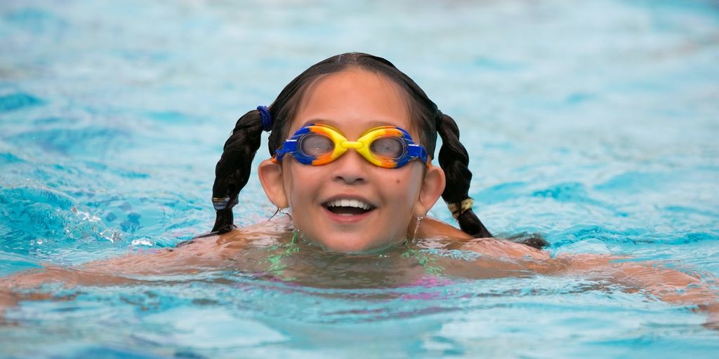 swimmer eating healthy food near pool with water bottles
