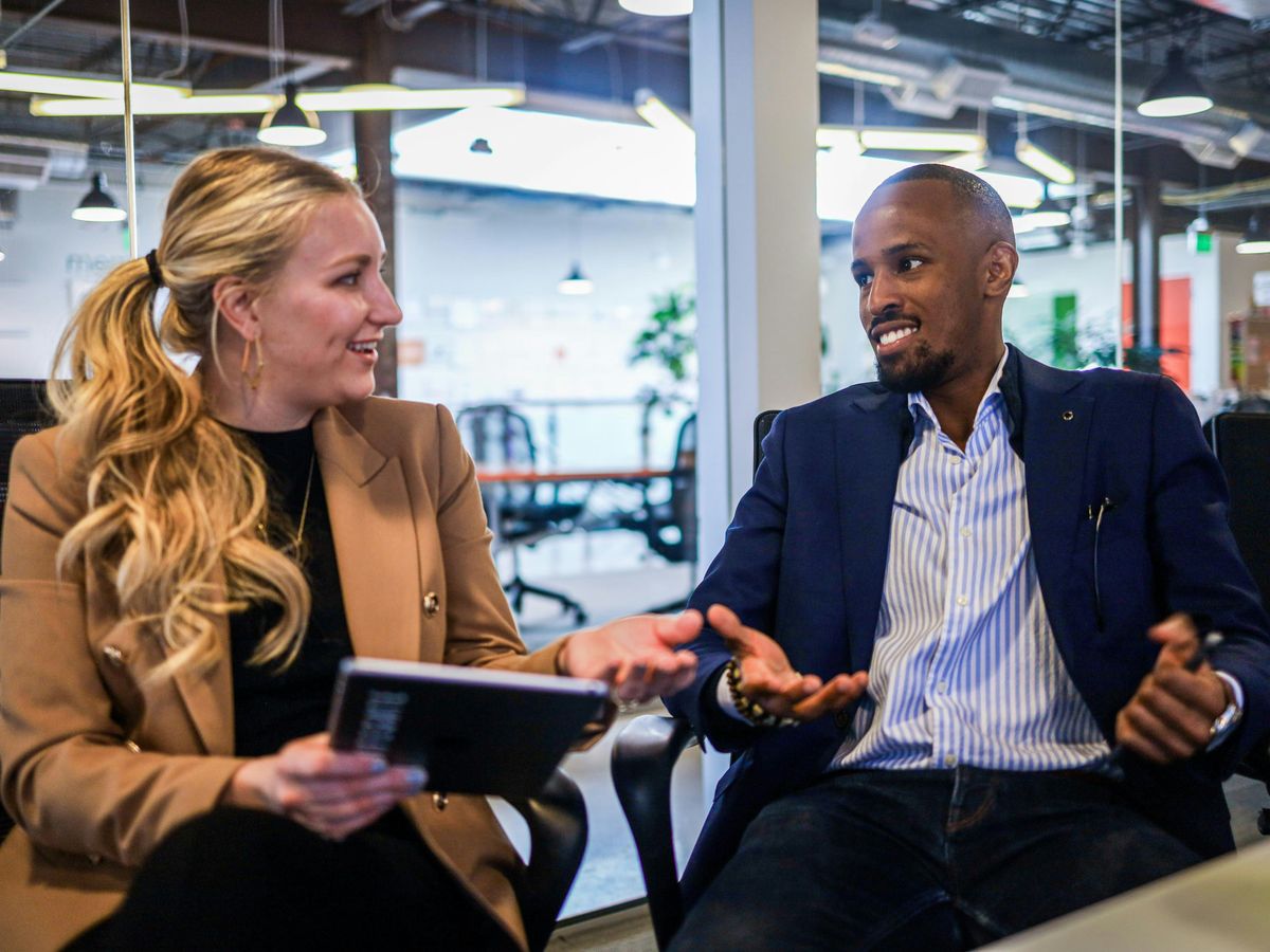 man in black suit jacket sitting beside woman in brown blazer