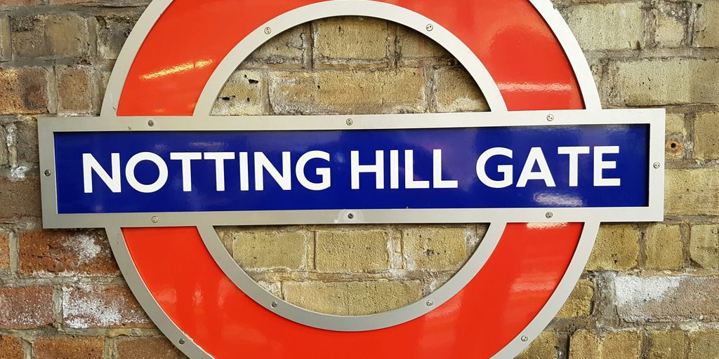 a sign on a brick wall that says notting hill gate
