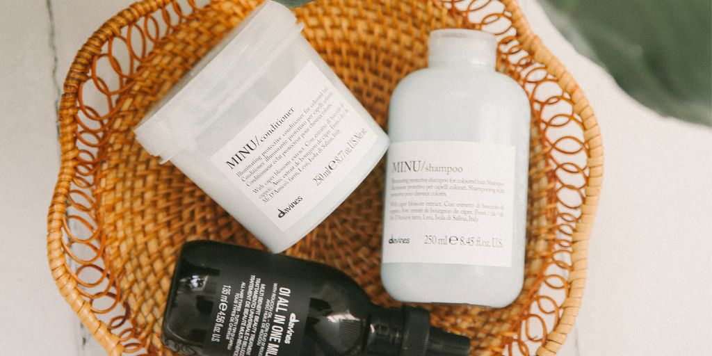 Hair care products arranged in a wicker basket with leaves.
