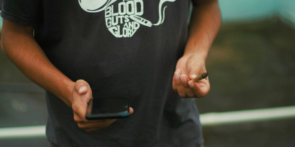 man in black and white crew neck t-shirt holding black smartphone