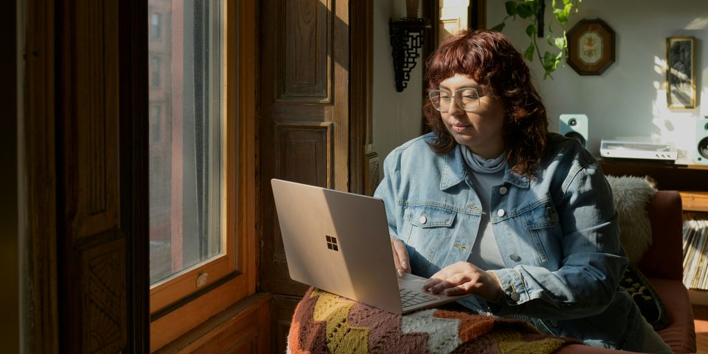 a woman sitting on a couch using a laptop computer
