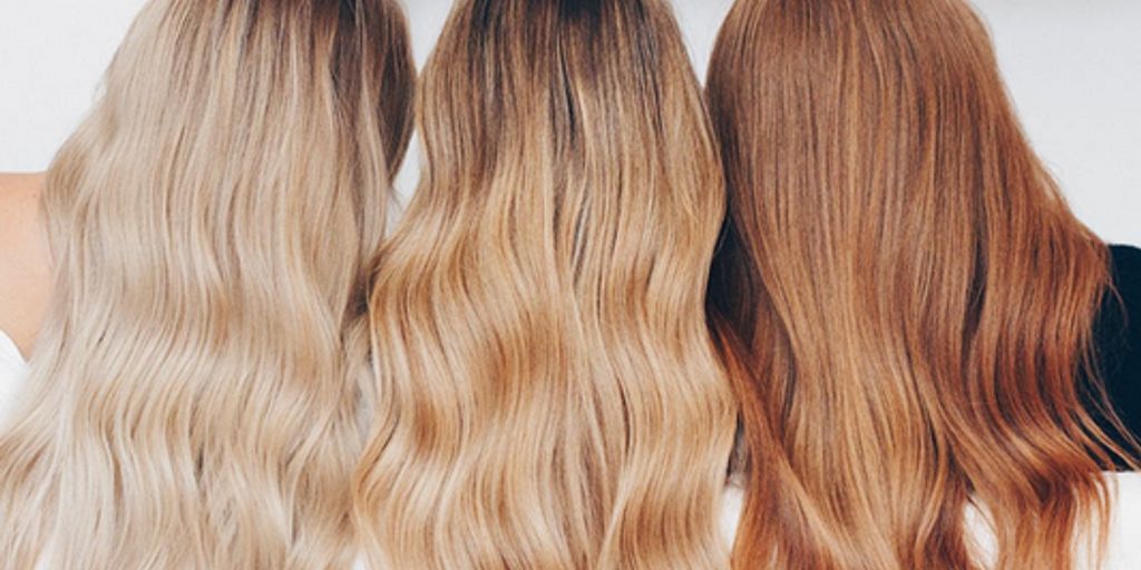 Three individuals showcasing different shades of long, wavy hair.