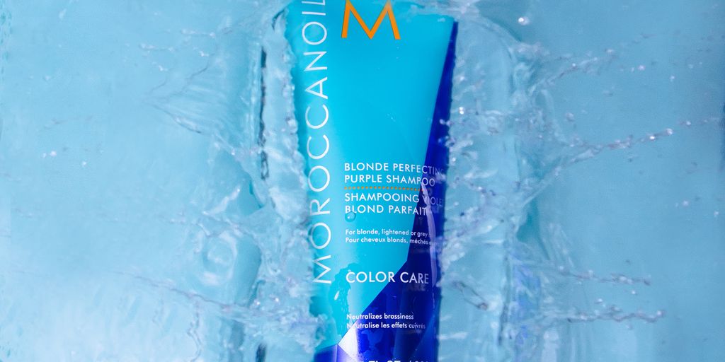 Moroccanoil shampoo submerged in water creating dynamic splash effects.