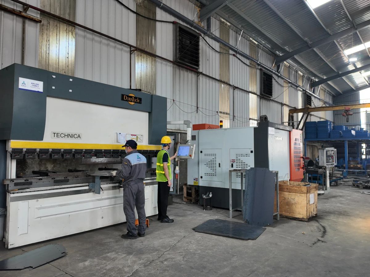 Industrial workspace featuring machinery and workers in safety gear.