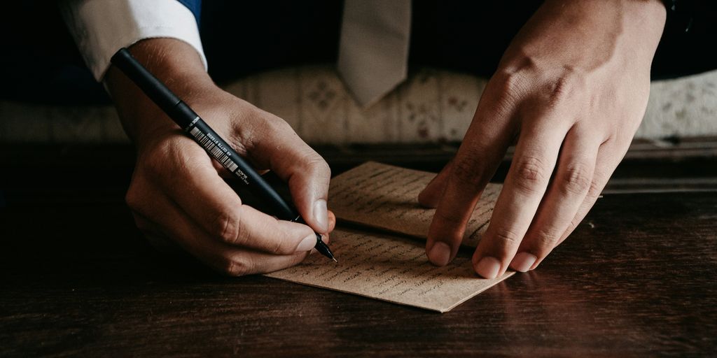 person writing on brown wooden table