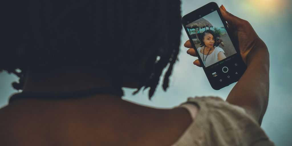 woman in white tank top holding iphone 6