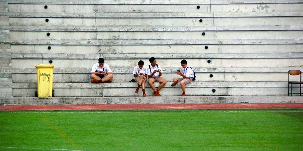 four boys wearing white shirt sitting near field