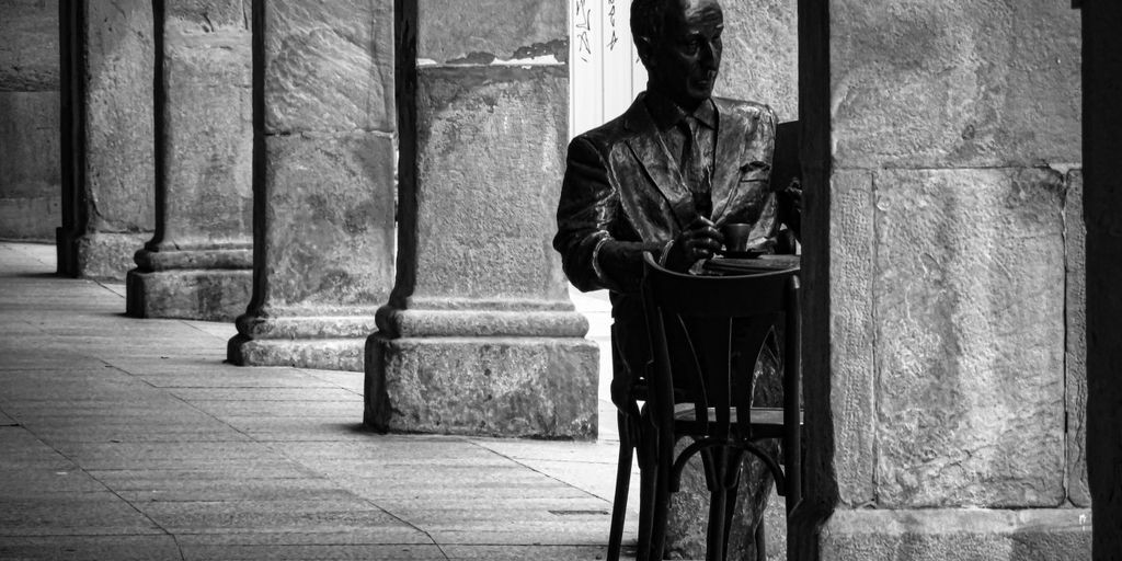 A statue of a man sits at a table.