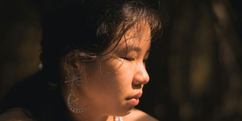 a woman with earrings on her head looking off into the distance