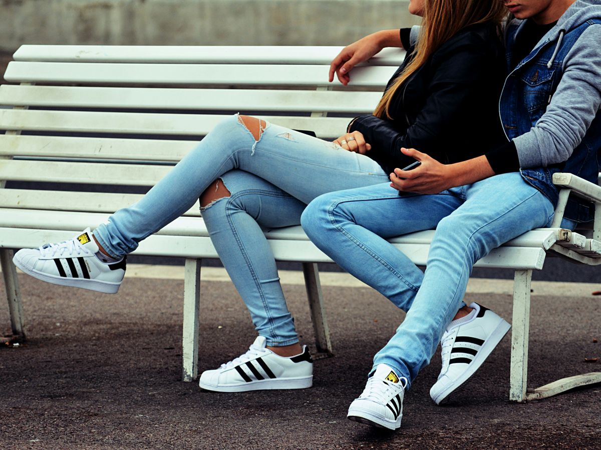 photo of couple sitting on white bench