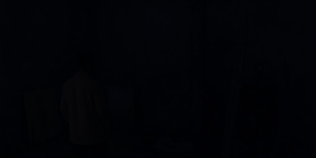 Somber figure in a dark, atmospheric art studio.