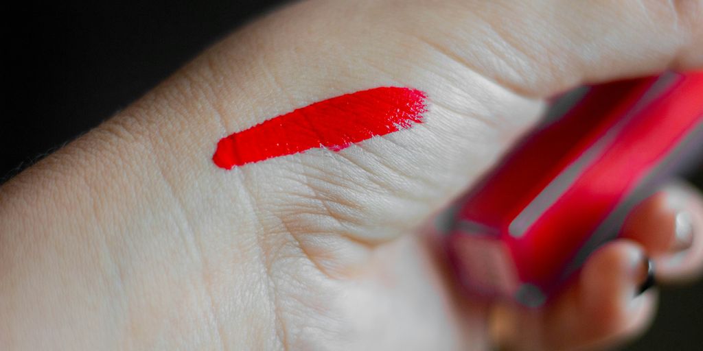 a person holding a cell phone with a red lipstick on it