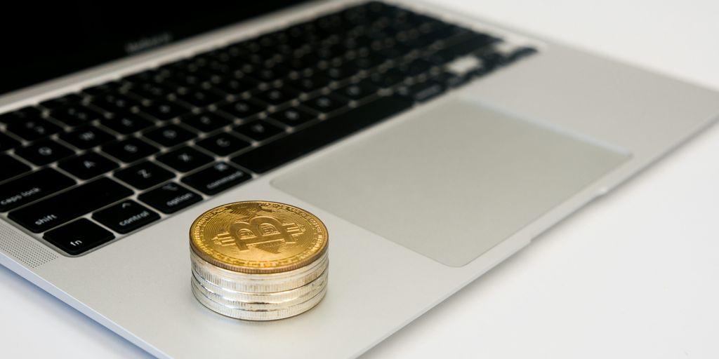 Coins stacked next to a laptop on a white surface.
