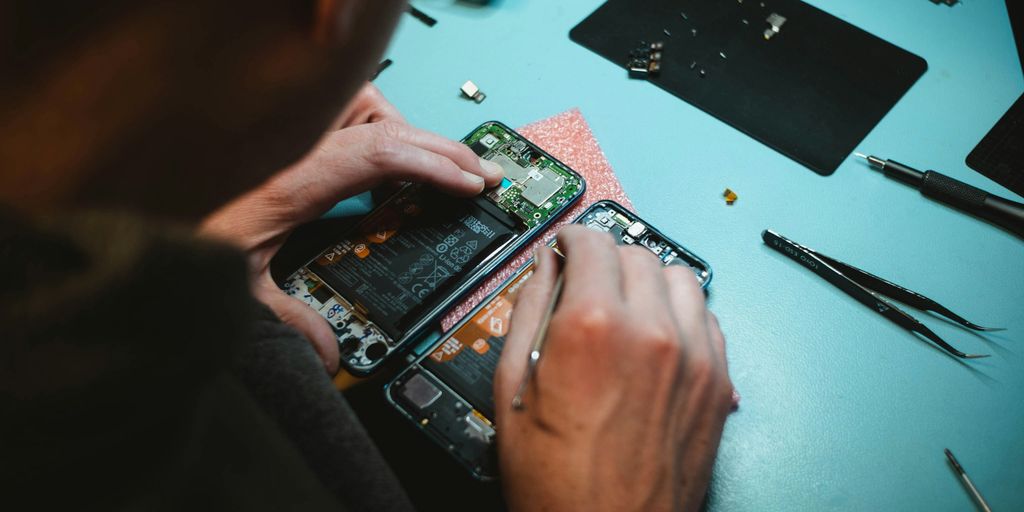person repairing smartphones under a lighted table