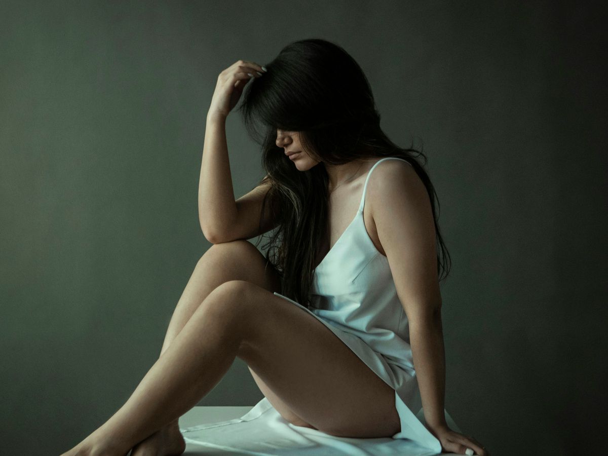 woman in blue tank top and white skirt sitting on white textile