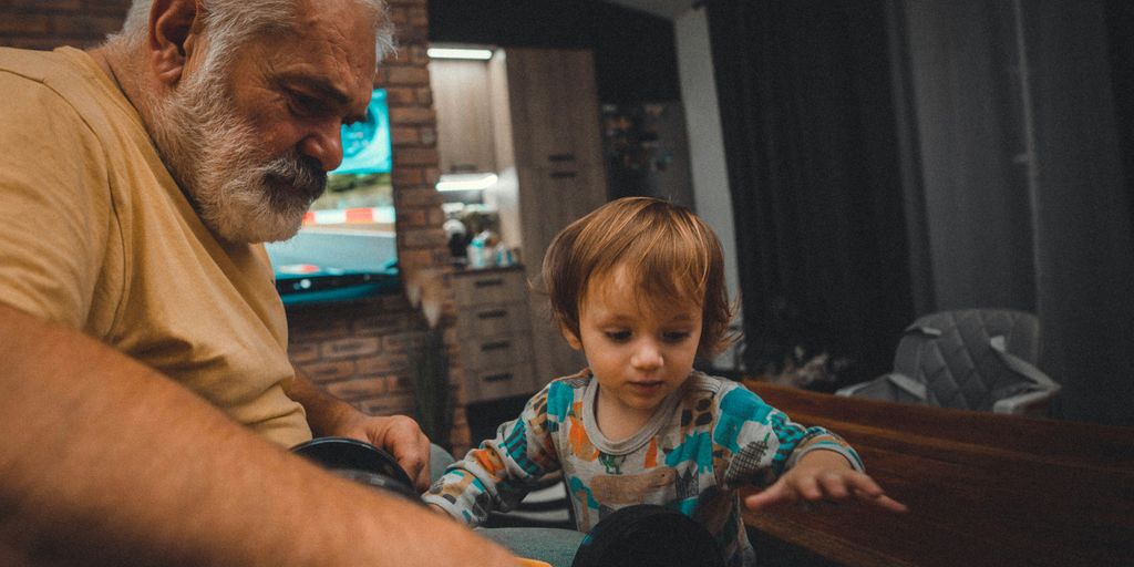 an older man and a young boy playing with a toy car
